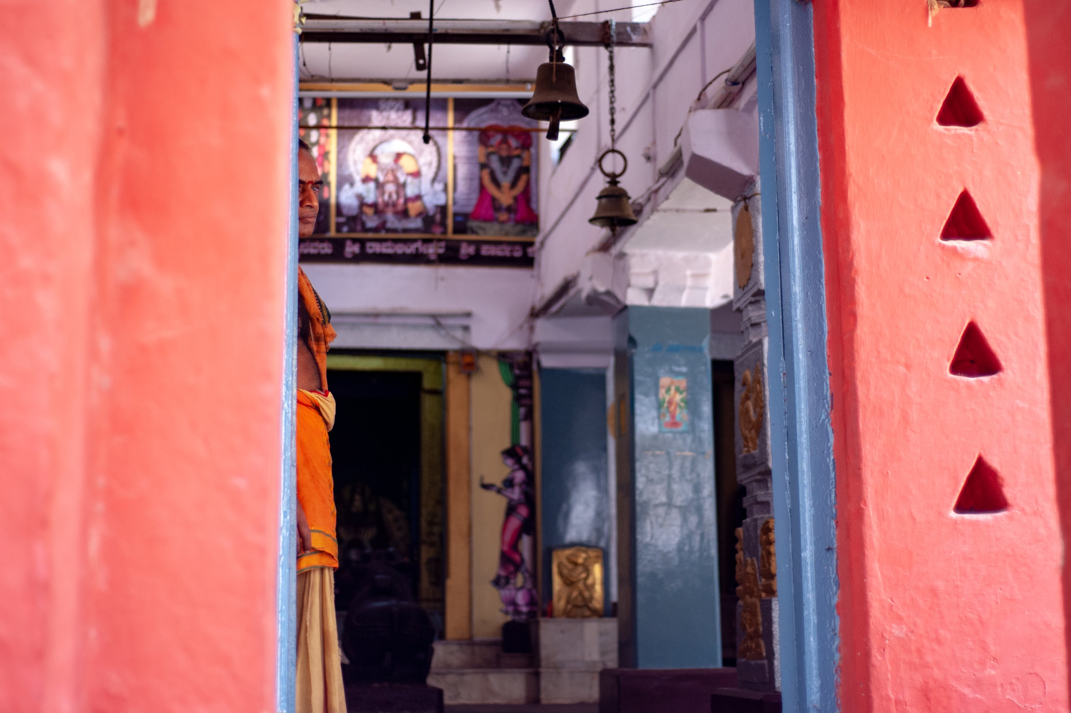 The temple priest of Chowdeshwari Temple in Chikpet, Bangalore watches the street through the temple's doorway. 