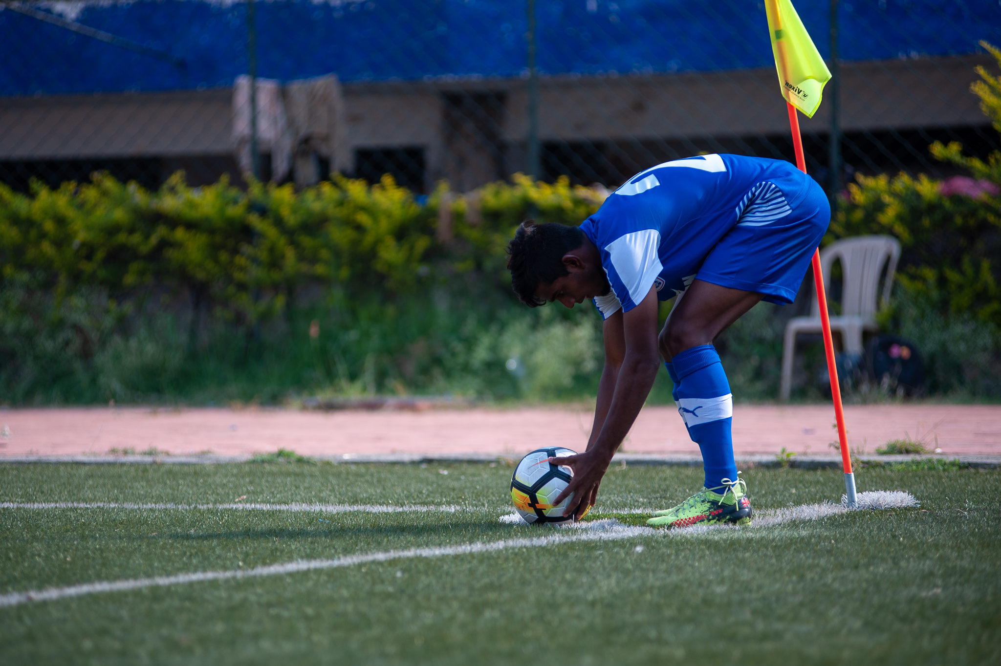 The left winger of Bengaluru FC B bends low to place the ball at the corner flag to take a corner.