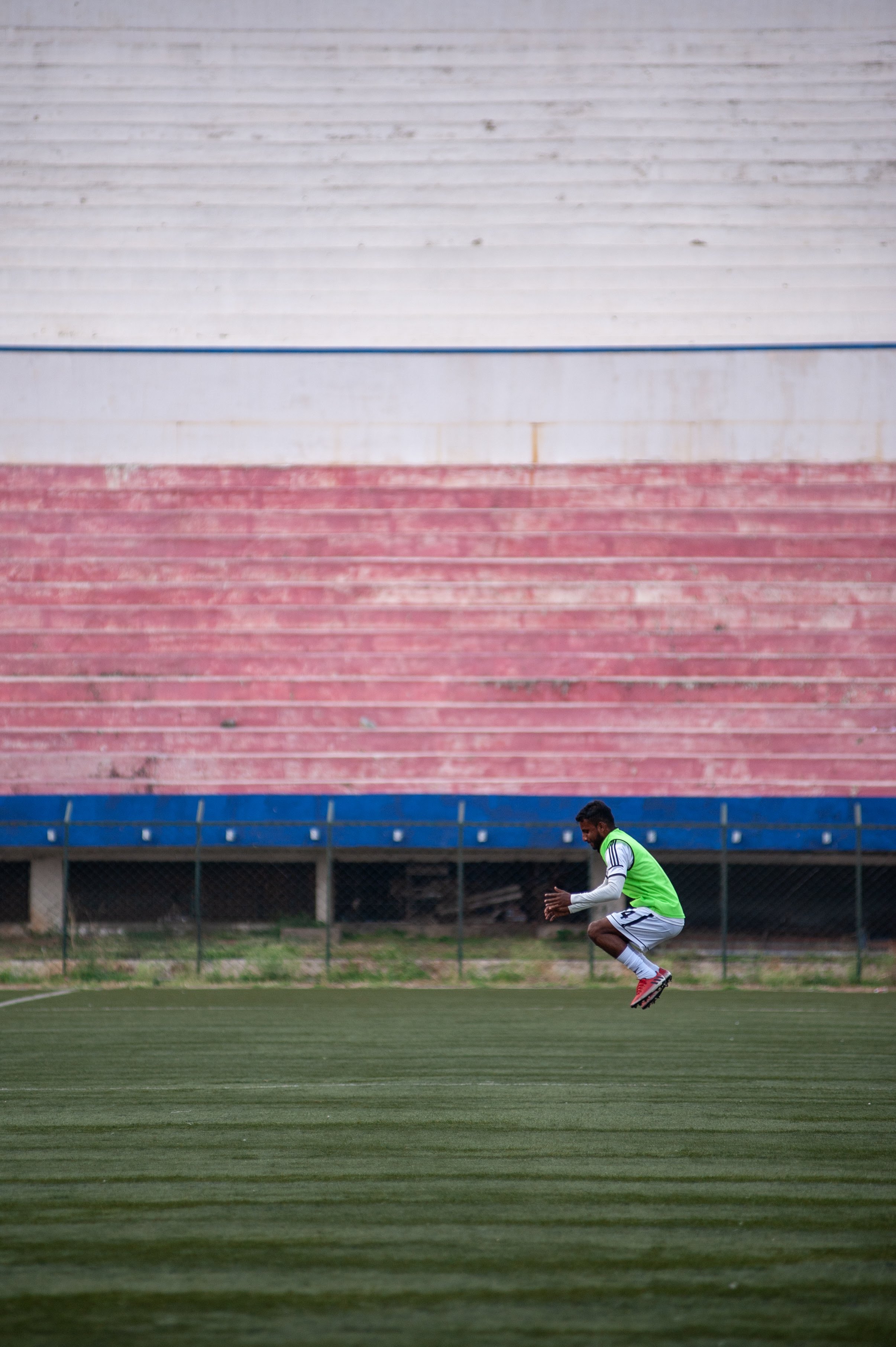 A Mohammedan Sporting player jumps up and down the width of the pitch to warm up during the half-time break.
