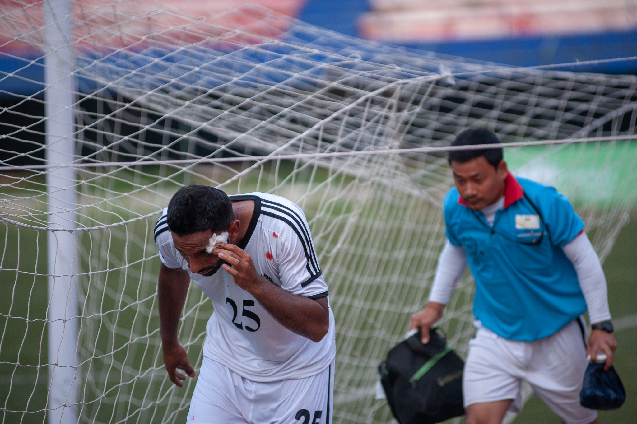 A Mohammedan Sporting player comes off briefly due to a head injury. He is seen here navigating his way to the bench from behind his goal.