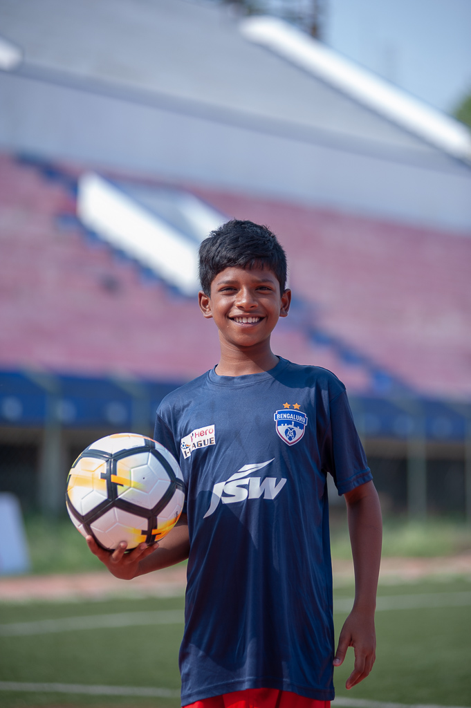 Portrait of a ball boy, named Joshua, holding a ball, looking into the camera and smiling.